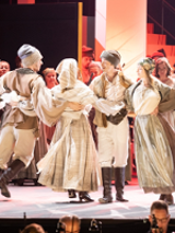 A group of dancers in folk costumes dance in a circle.