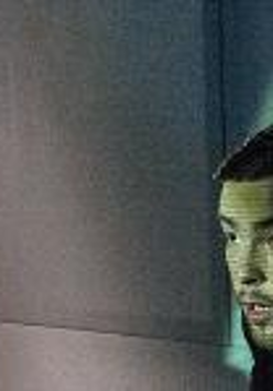 On the right side of the picture the face of a man, who looks frightened. Dark background, with a light streak.