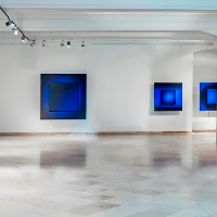 A bright room with white walls and square pictures on them in blue colours