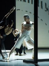 Two ballet dancers - a woman in black dress and a man in white garment in dance poses.