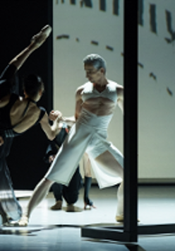 Two ballet dancers - a woman in black dress and a man in white garment in dance poses.
