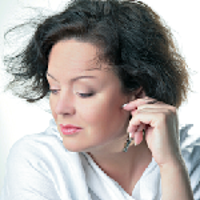 Photo of the face of the singer dressed in white blouse and looking down with her hand touching her ear