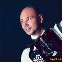 Photo of Marcin Wyrostek looking right and holding an accordion