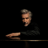 Photo of the artist - a man in black clothes on the black background