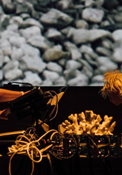 The photo shows the musicians during a performance, leaning over electronic instruments
