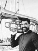 Black and white photograph of the artist - a man holding a tuba on his shoulder