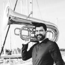 Black and white photograph of the artist - a man holding a tuba on his shoulder