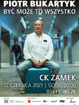 Photo of the artist in a white shirt and headphones, who is sitting on a turquoise pouf in a public space, probably in the underground passage of a train station or subway