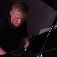 Photo in dark colours - a man playing the piano