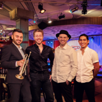 Photo of a band - four man, one of them is holding trumpet