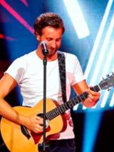 Photo of the artist - a man standing by the microphone and playing the guitar