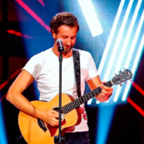 Photo of the artist - a man standing by the microphone and playing the guitar