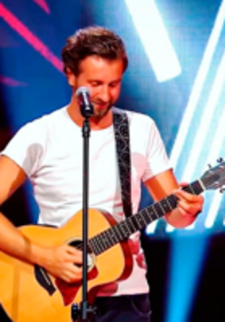 Photo of the artist - a man standing by the microphone and playing the guitar