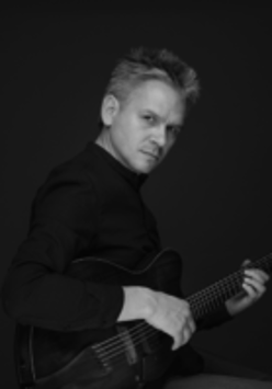 Black and white photo of the musician - a man holding a guitar and looking into the camera