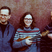 Photo of band members - one woman holding ukulele between two men