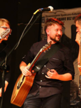 Three men playing guitars on a stage