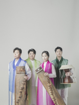 Photo of the band - three men and one woman stnding in their folk clothes with their musical instruments.