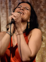 A picture of a woman singing to the microphone, which she holds in her hands.