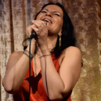 A picture of a woman singing to the microphone, which she holds in her hands.