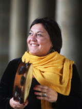 Photo of the artist - a smiling woman holding a musical instrument in her hands