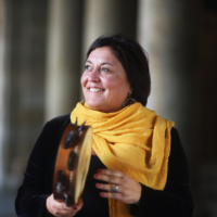 Photo of the artist - a smiling woman holding a musical instrument in her hands