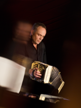 Photo of the musician- a man playing the bandoneon