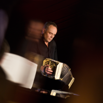 Photo of the musician- a man playing the bandoneon