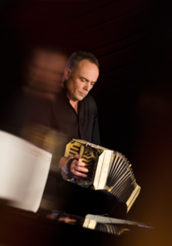 Photo of the musician- a man playing the bandoneon