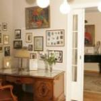 Photo of one of the rooms in Willa wśród Róż: antique desk and chair, pictures on the wall, open door to another room