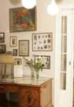 Photo of one of the rooms in Willa wśród Róż: antique desk and chair, pictures on the wall, open door to another room