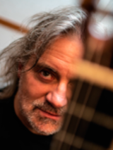 Photo of the artist - a face of a man behind guitar's neck