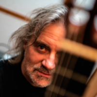 Photo of the artist - a face of a man behind guitar's neck