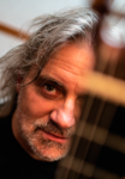 Photo of the artist - a face of a man behind guitar's neck