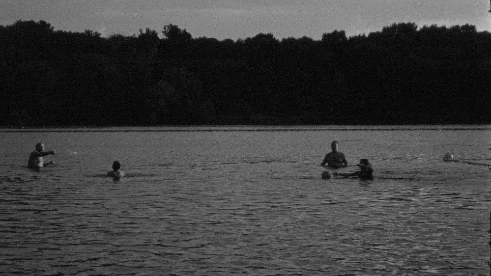 One of the exhibition works - black and white picture of a few people in a lake or river. Forest as a background.