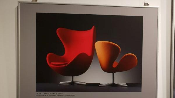 Photo of a picture hanging on the wall: two modern armchairs, one red and one orange