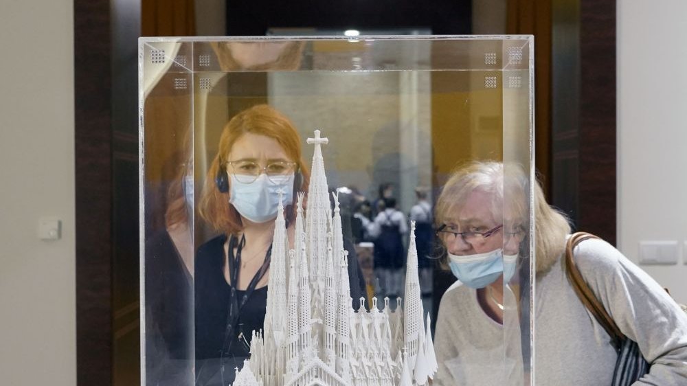 A mockup of Gaudi's cathedral in a glass case and two women watching it.
