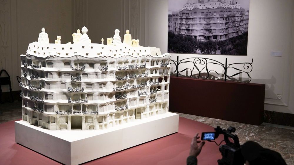 A model of one of the buildings designed by Gaudi. In the background a black and white photo of this building on the wall