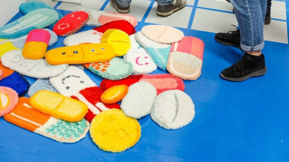 Photo of artist's works - pieces of a soft, colourful cloth in a shape of pills.