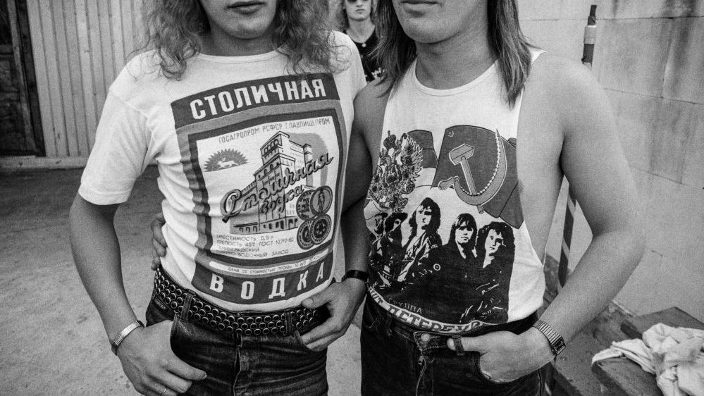 Black and white photo of two people in T-shirts with Russian inscriptions and motives.