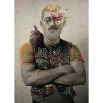 The picture of a man with folded arms in colourful vest. A part of his face is covered by flowers