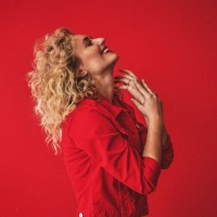 Photo of the singer dressed in red clothes on a red background