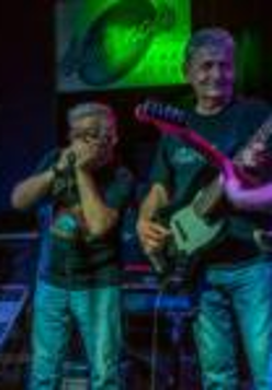 The picture presents 3 men playing instruments on a stage.