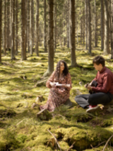 Photo of the duo Ponad Chmurami - a man and a woman sitting on grass in the forest