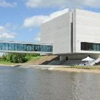 Photo of Porta Posnania: a concrete building by a river.
