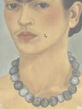 A woman with dark hair tied in a bun. The woman has a light blouse with lace trim and a necklace of dark beads. The background is dark gray.