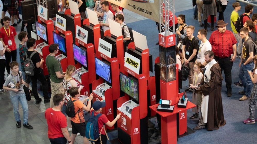 A hall with game machines and people playing on them.