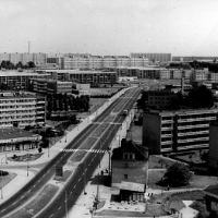 A black and white photograph of a bird's eye view of a landscape with apartment blocks and a two-lane road running diagonally