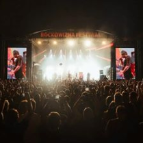 Photo from the concert: an illuminated stage and a crowd of people in front of it