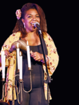 Picture of the singer - afro american woman standing and singing to a microphone; a woman holds maracas in her hands
