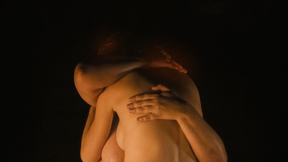 Photo of two naked people without visible faces, who are hugging.